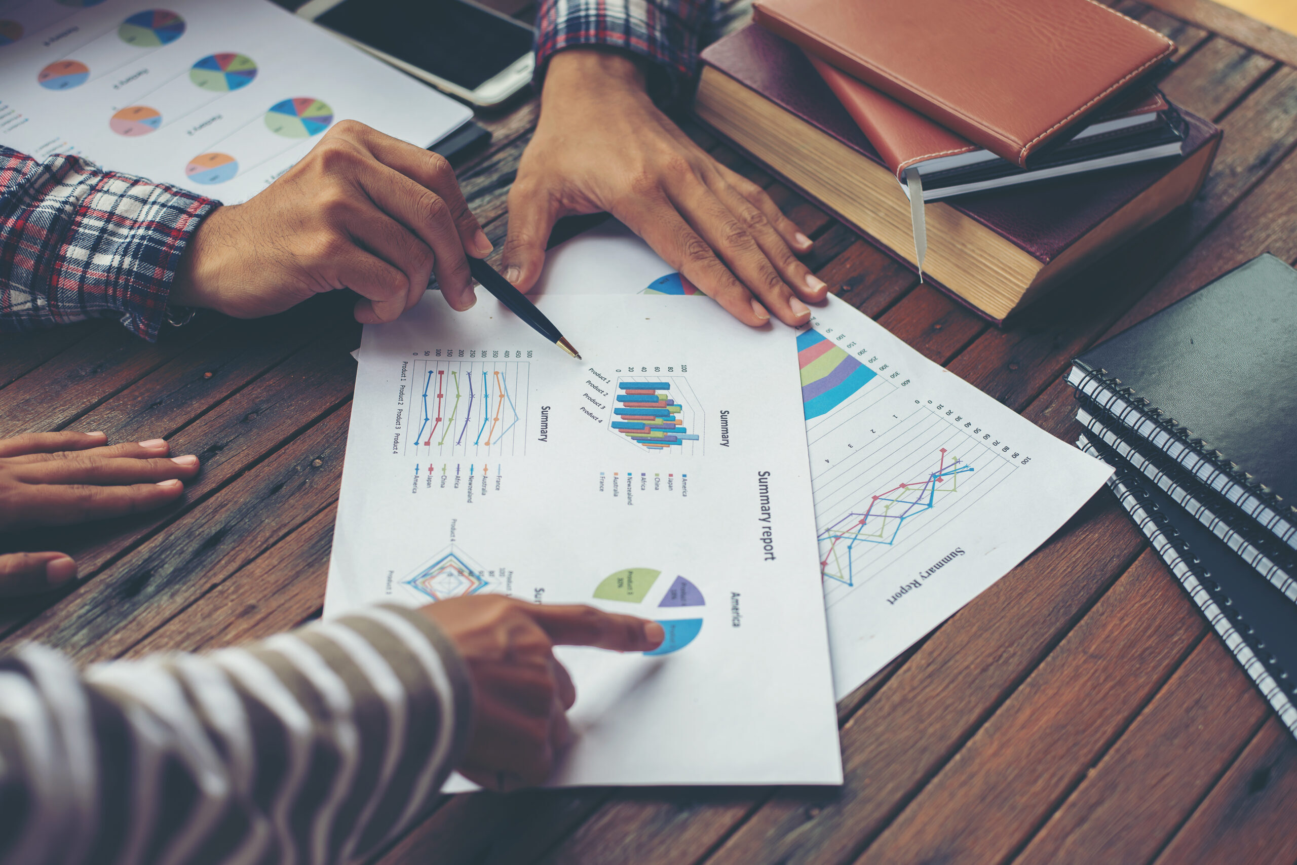 Auf einem Tisch liegen Dokumente einer Kommunalen Pflegestrukturplanung und mehrere Hände zeigen auf abgedruckte Grafiken.