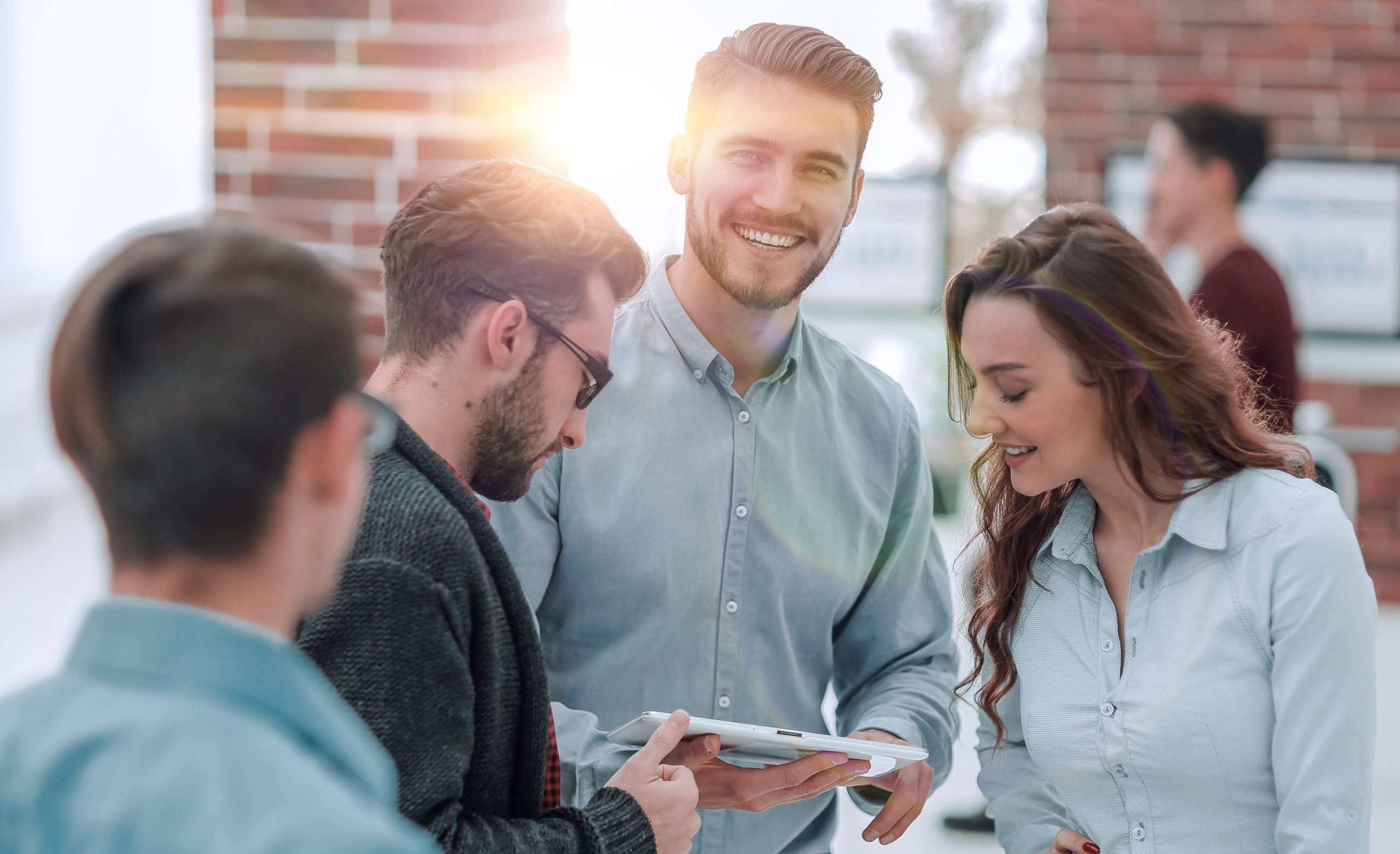 Drei Menschen stehen nebeneinander und schauen auf ein Tablet.
