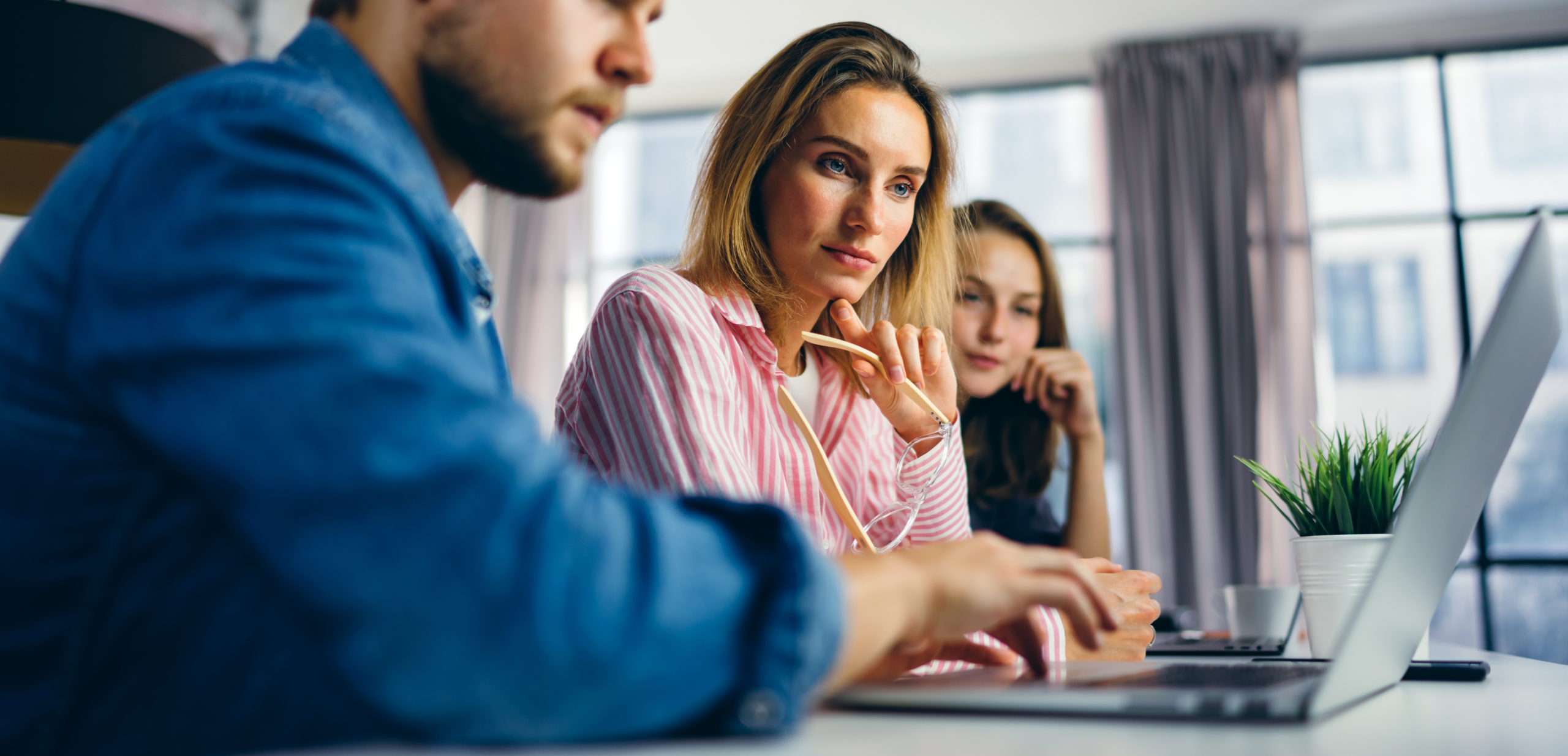 Drei Berater von contec arbeiten gemeinsam am Notebook eine Organisationsanalyse aus.