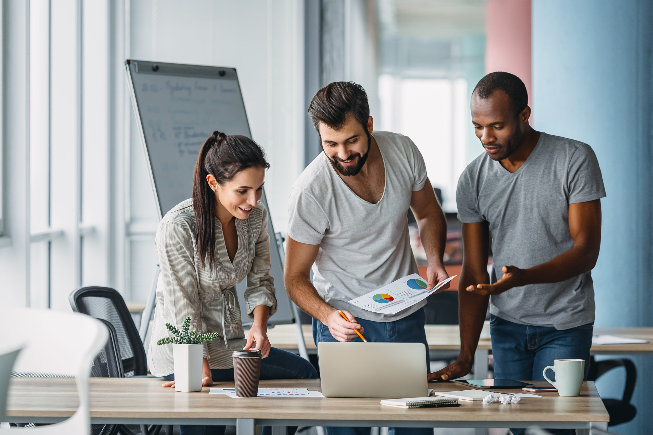 Drei Kolleg:innen sprechen über einen Laptop gebeugt über die Analysen der Pflegestrukturplanung.