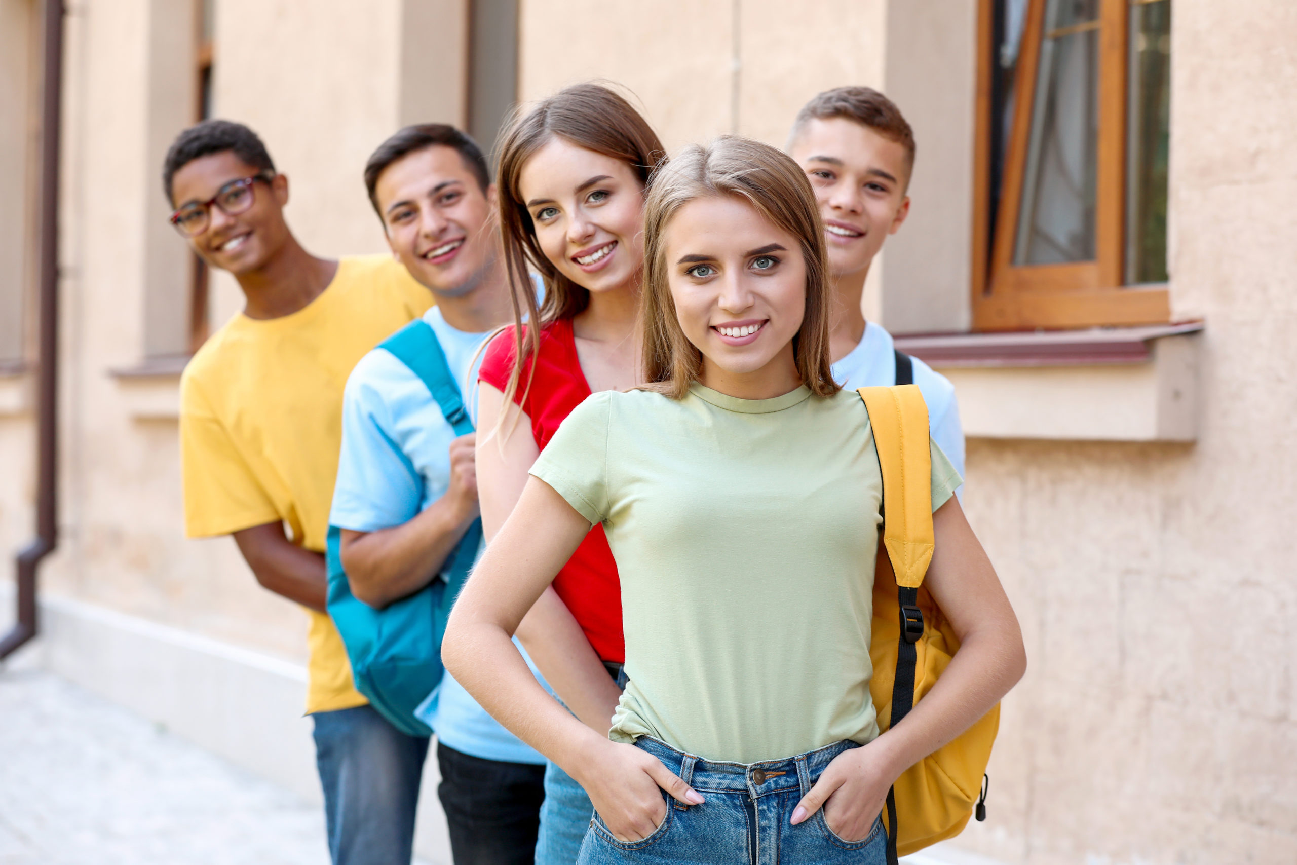 Fünf junge Menschen stehen hintereinander und lächeln in die Kamera.