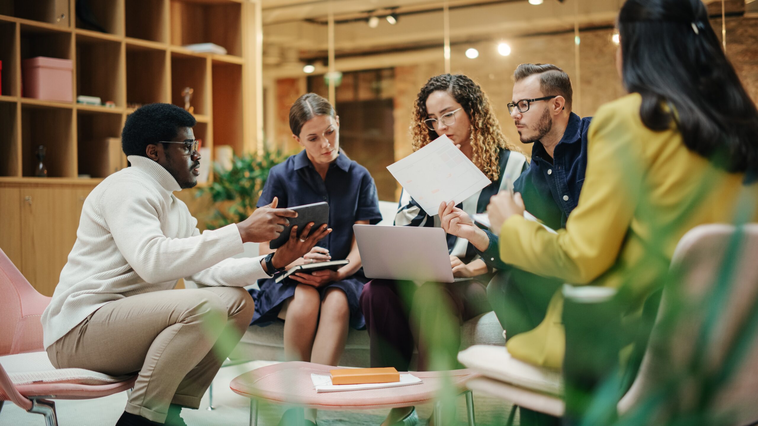 Vier junge Menschen sitzen im Kreis und sprechen miteinander über den Wettbewerbsvorteil Nachhaltigkeit, ESG und Grean Deals.