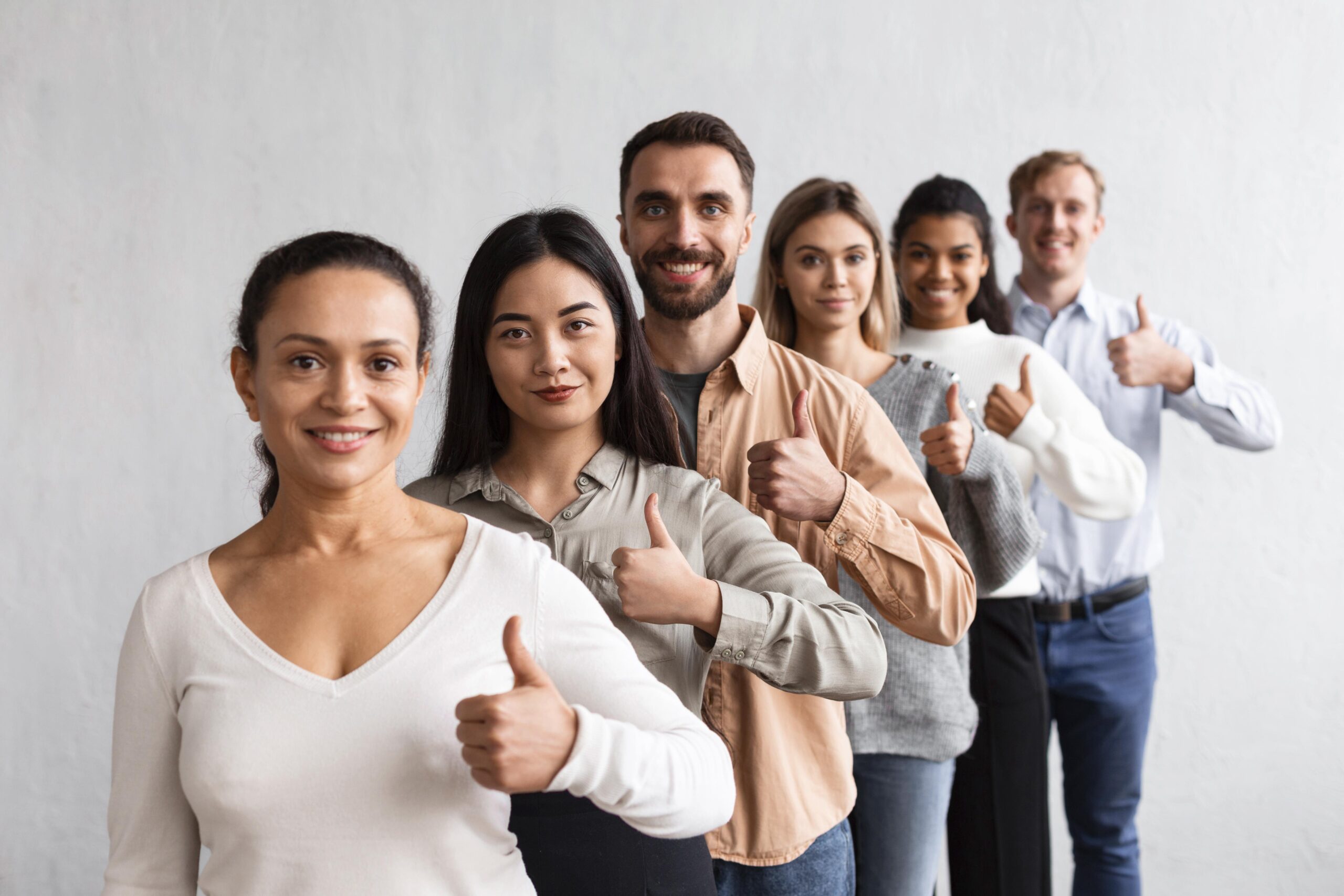 Sechs junge Leute stehen aufgereiht hintereinander und heben ihren Daumen hoch. 