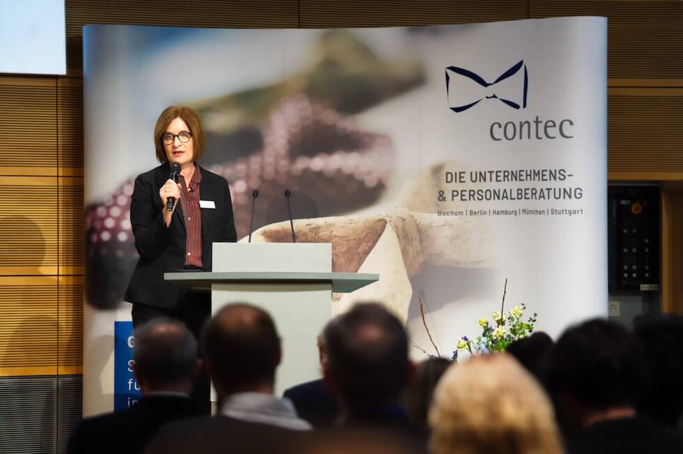 contec Bereichsleiterin Eva Lettenmeier auf einer Bühne während einer Moderation
